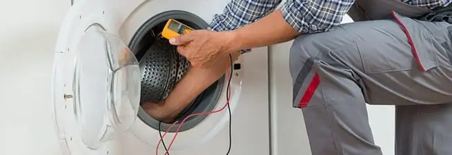 Dryer repair technician inspecting and repairing a clothes dryer in Kansas City, KS