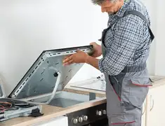 Appliance repair technician installing a built-in cooktop in Kansas City, KS