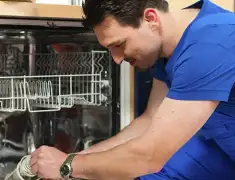 Dishwasher repair technician inspecting and servicing an open dishwasher in Kansas City, KS