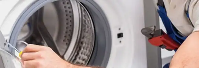 Appliance technician repairing a clothes dryer drum and internal parts in Kansas City, KS