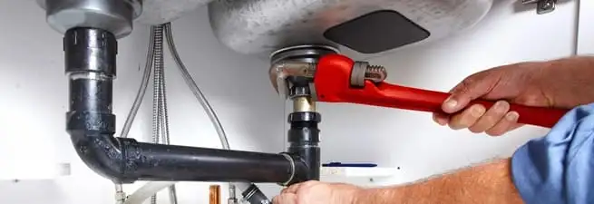 Garbage disposal repair technician tightening the sink drain and disposal connection in Kansas City, KS