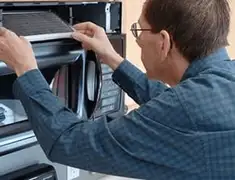 Appliance repair technician replacing a microwave vent filter in Kansas City, KS