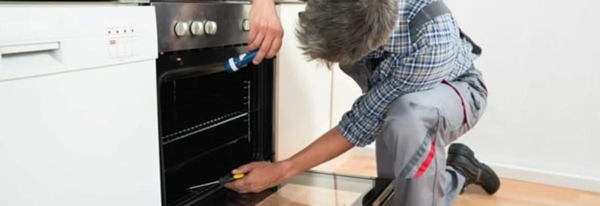 Oven repair technician inspecting and servicing an electric oven in Kansas City, KS