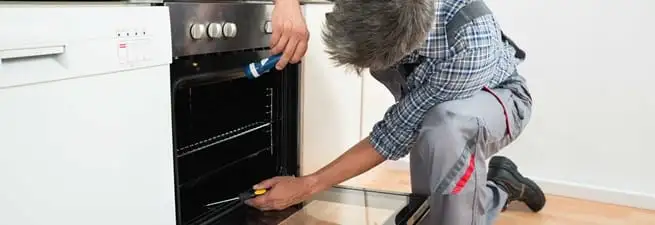 Oven repair technician inspecting and servicing an electric oven in Kansas City, KS