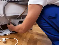 Appliance repair technician fixing refrigerator water line and connections in Kansas City, KS