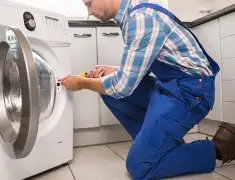 Washing machine repair technician servicing a front-load washer in Kansas City, KS