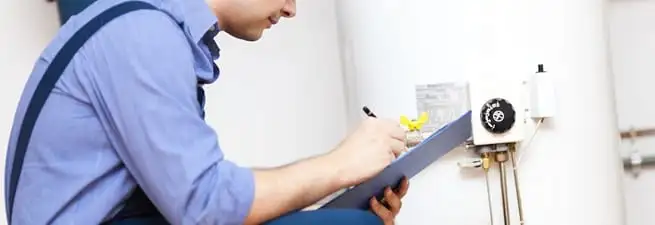 Water heater repair technician inspecting the unit and recording service notes in Kansas City, KS