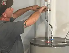 Water heater repair technician tightening supply line connections in Kansas City, KS