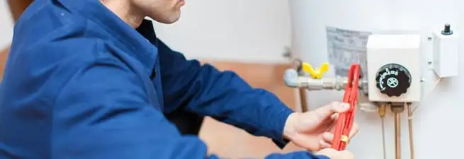 Water heater repair technician adjusting the temperature control and gas valve in Kansas City, KS
